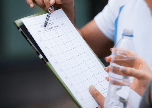Client receiving personalized fat-loss guidance after hitting a weight loss plateau, trainer explaining progress metrics